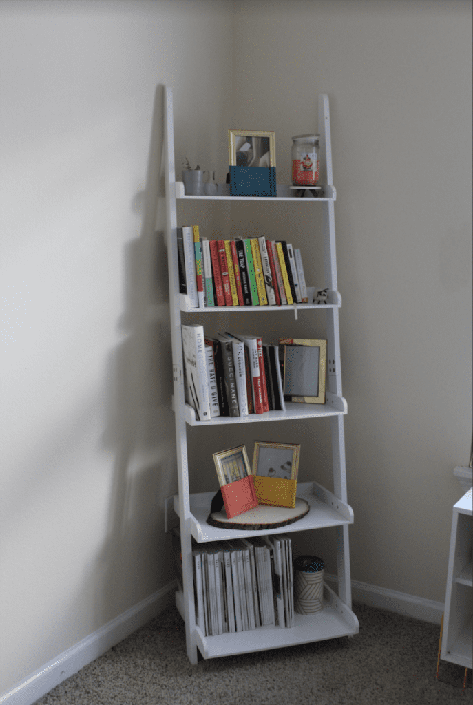 book shelf with magazines, books, gold frames, and candles