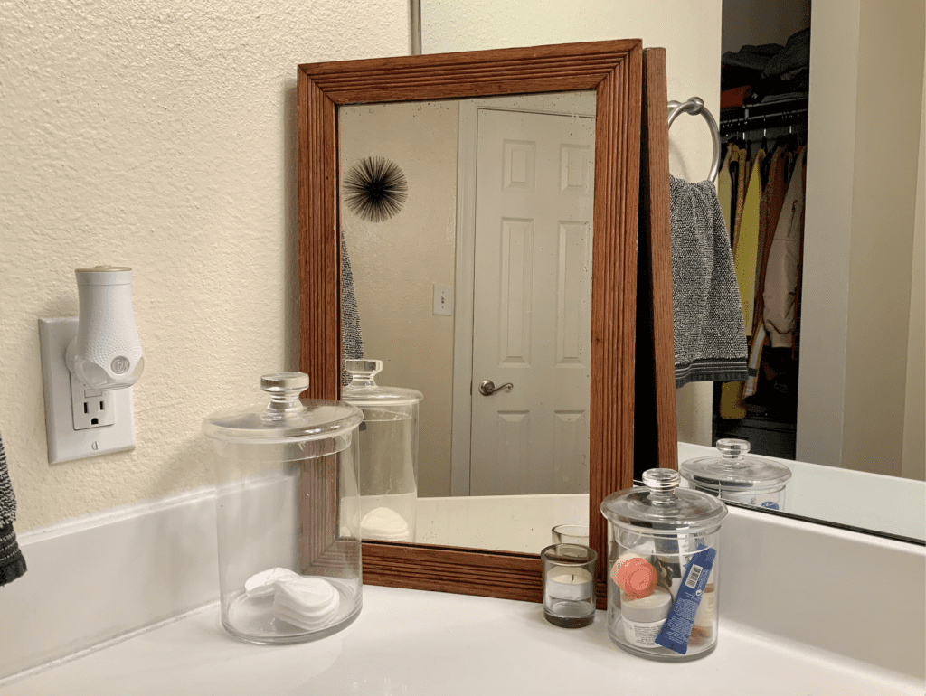 Thirfted wood mirror on bathroom counter with accessories