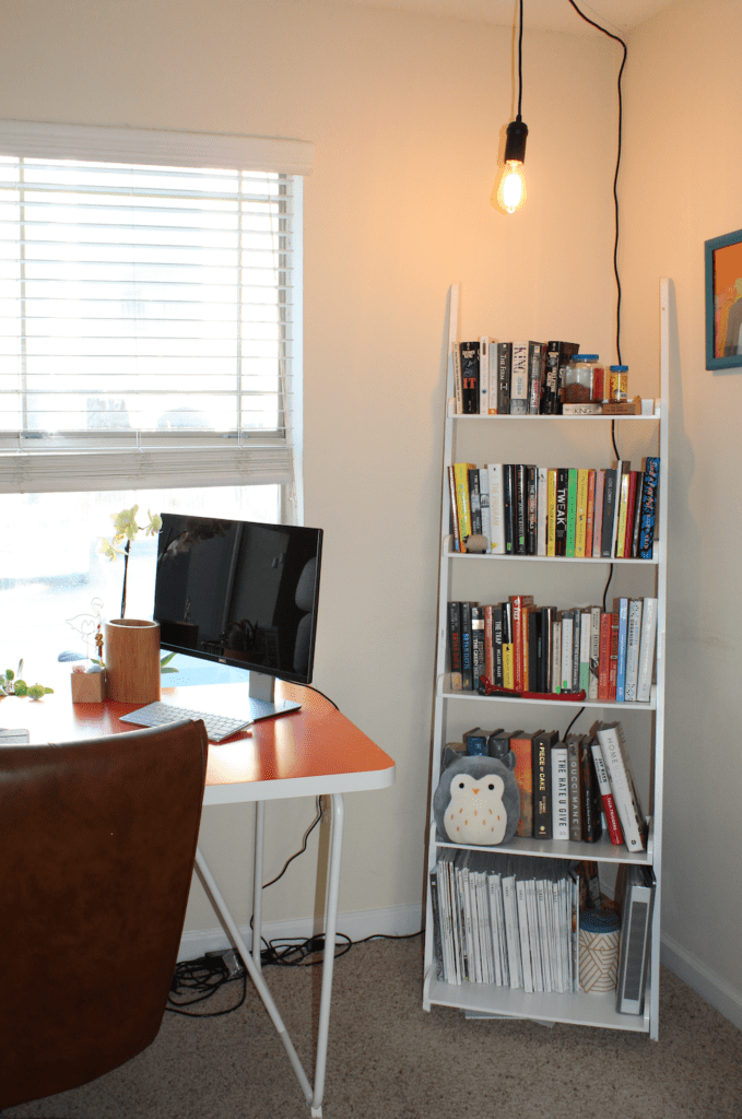 Corner of multipurpose office with a bookshelf and industrial pendant light