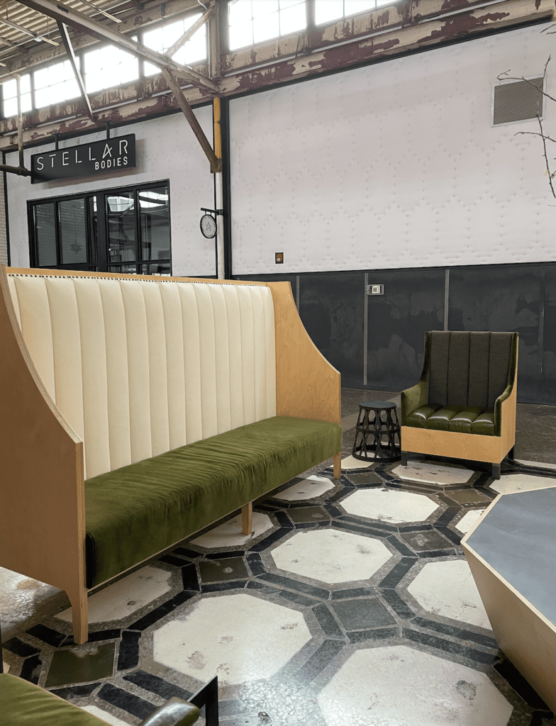 Olive green velvet, white faux leather, a and pale wood seating area with hexagonal tiles on floor - The Works ATL