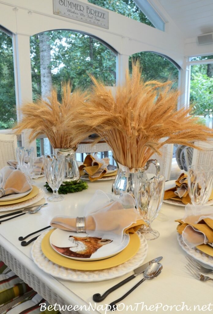 Between naps on the porch Dapper dressed animals unique thanksgiving tablescape with plates with well-dressed animals, yellow and white chargers, crystal water glasses, and pampas grass