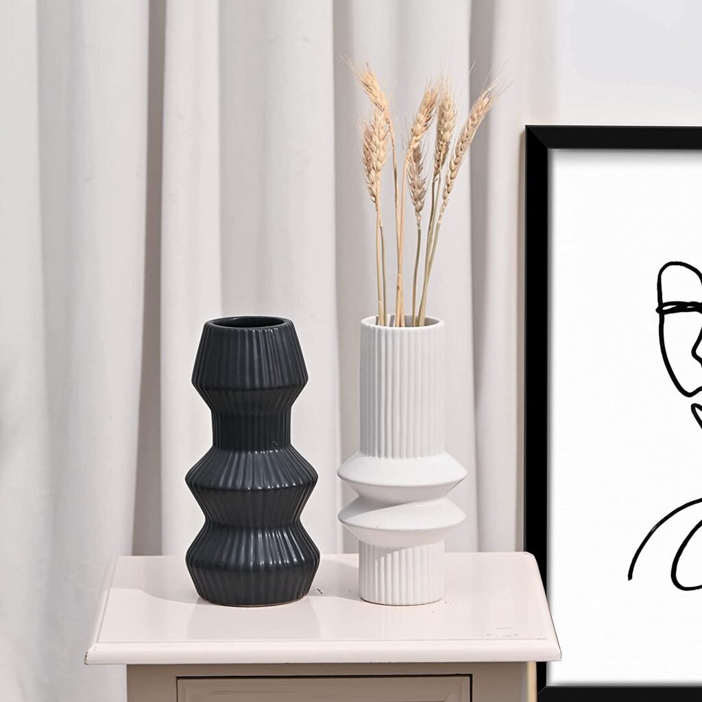 Textured modern ribbed vases in black and white sitting on a table with foliage inside - thanksgiving accent pieces
