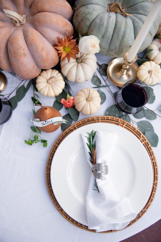 darling down south whimsical pumpkins thanksgiving tablescape with pastel-colored pumpkins, bright white plates, and bright white napkins