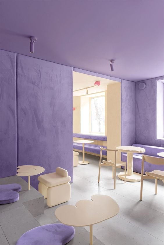 Commercial interior space with soft purple suede walls and pale plywood furniture accents