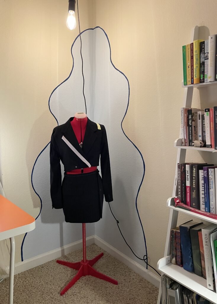 Office corner with a baby blue splotch painted with a navy blue rim. A red mannequin with a DIY outfit on it is standing in front of the corner