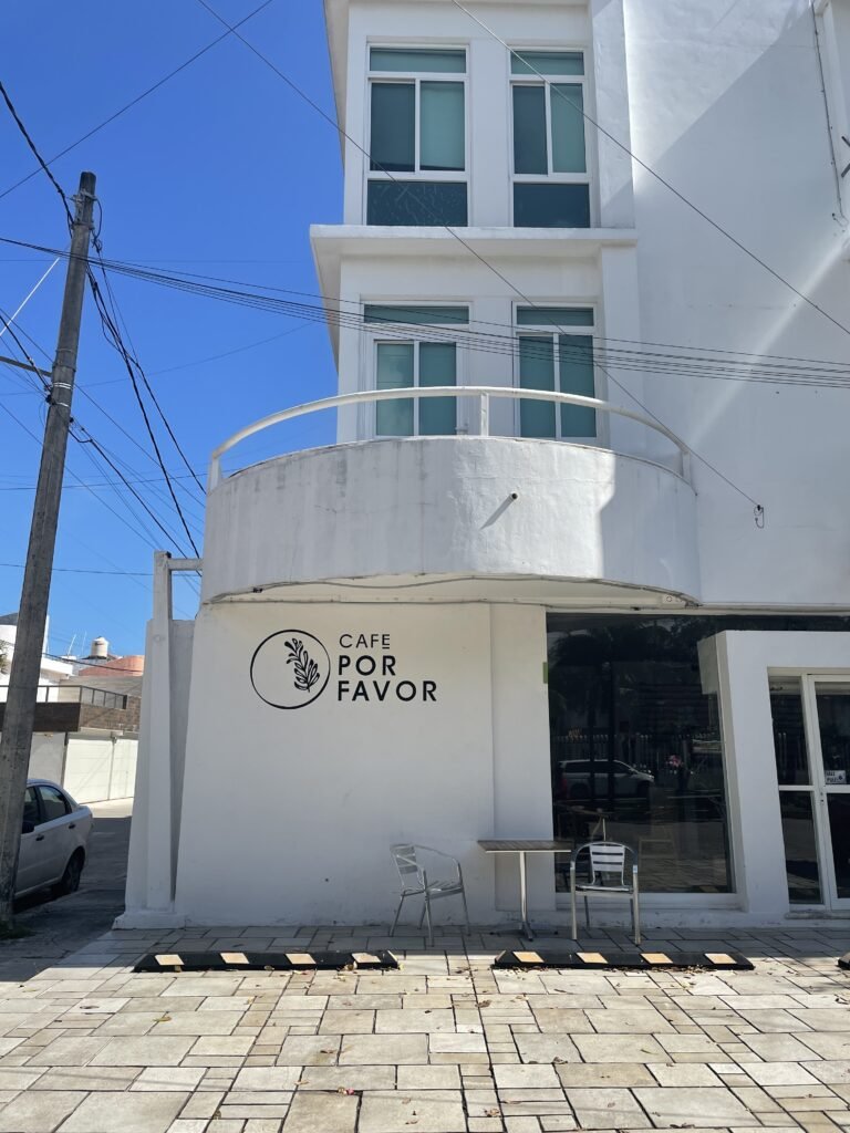 The exterior of a coffee shop called Cafe Por Favor - white stucco details with a curved balcony