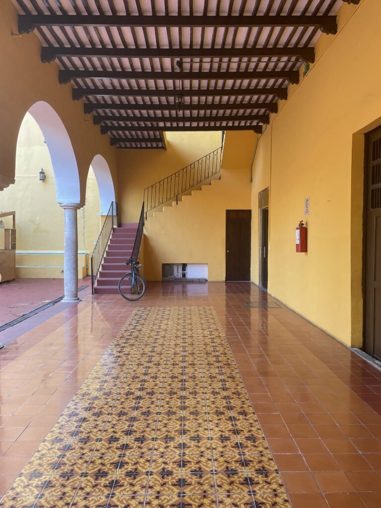 Bright yellow outdoor/indoor space with traditional Spanish architecture and colorful tiled flooring