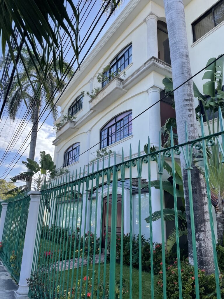 Traditional Spanish Cancun architecture apartment building with a bright green iron fence in front
