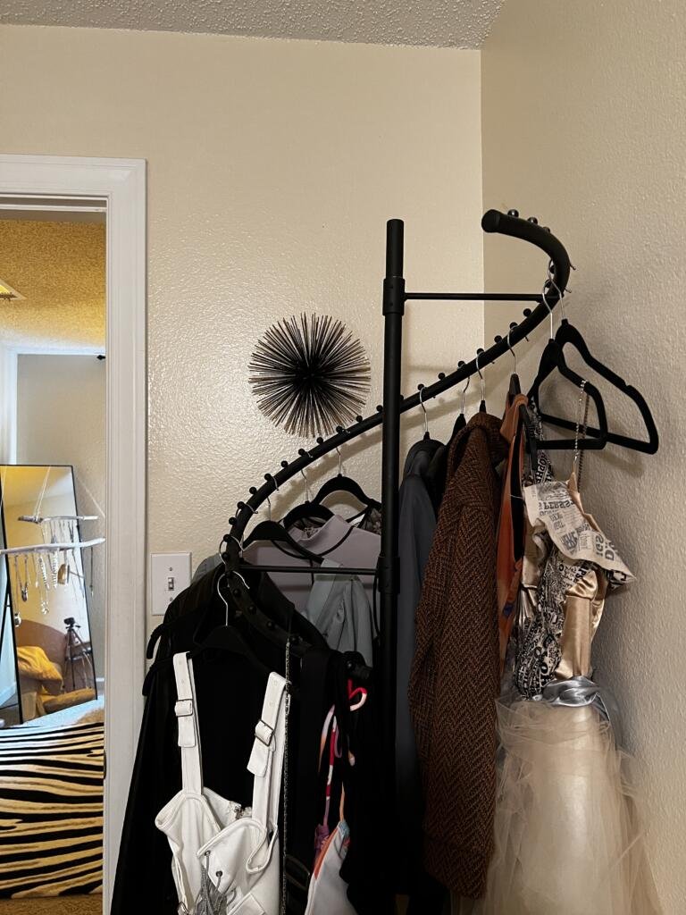 black spiral clothing rack with some feature clothing pieces on it - space saving option for small closet organization