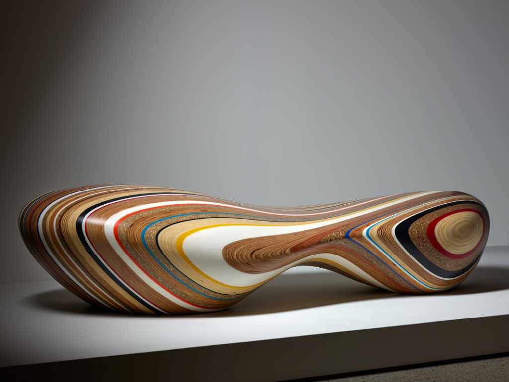 Brodie Neill's Remix chair made of discarded materials from construction sites, including timber and plastics. It's a curvy, organic-shaped chair with two bulbous ends