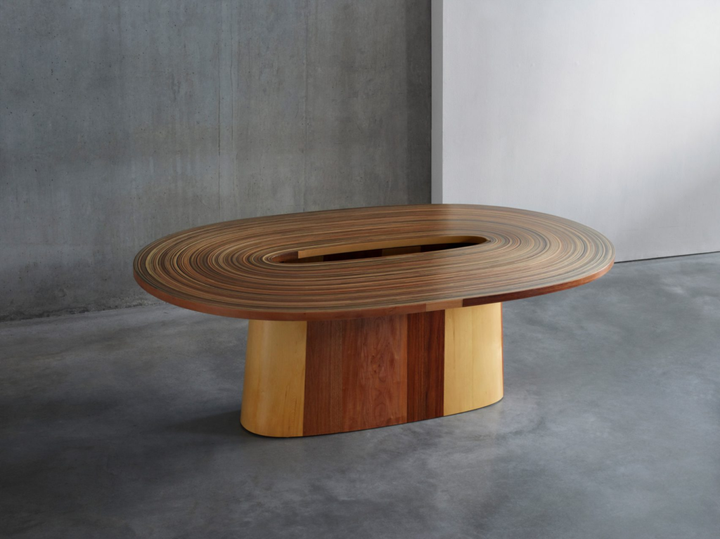Brodie Neill's Recoil table made out of reclaimed wood from a flooded forest in Tasmania. The tabletop has a hollow oval in the middle and coiled wooden slats forming the tabletop