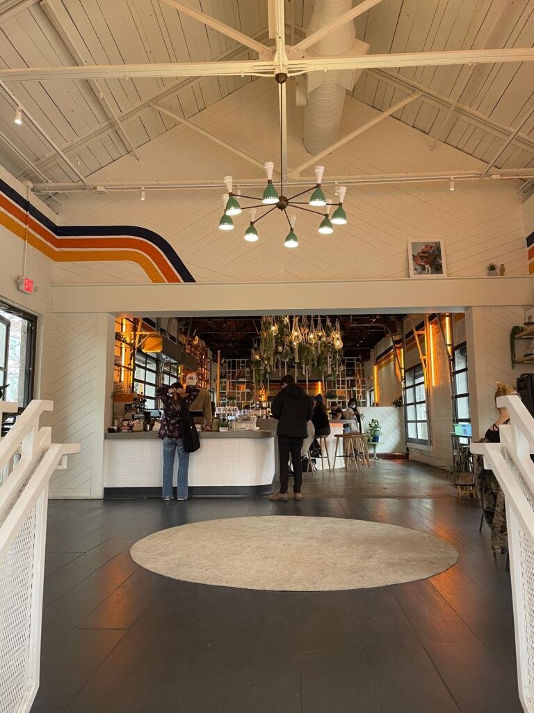 View upon entering Muchacho with a black and teal pendant light, and a retro yellow orange and navy stripe on the wall