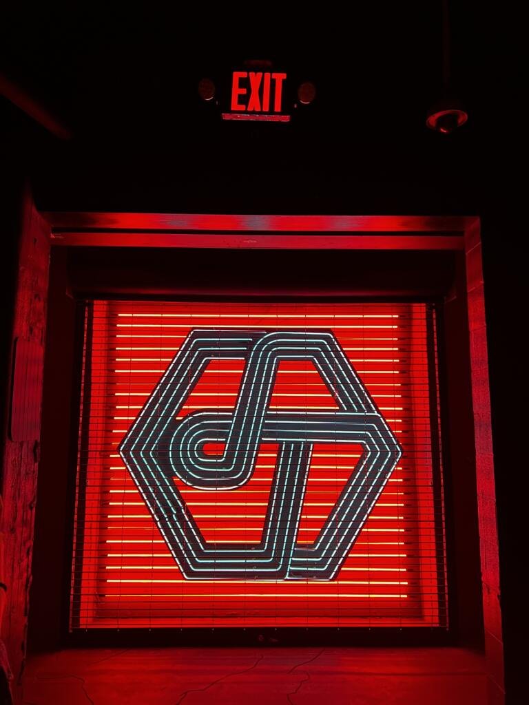 Little Trouble's instagrammable entrance with their logo and moody neon lights