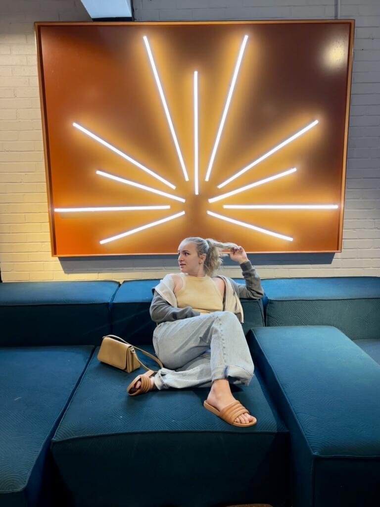 Posing on blue couch in front of an orange and neon art piece