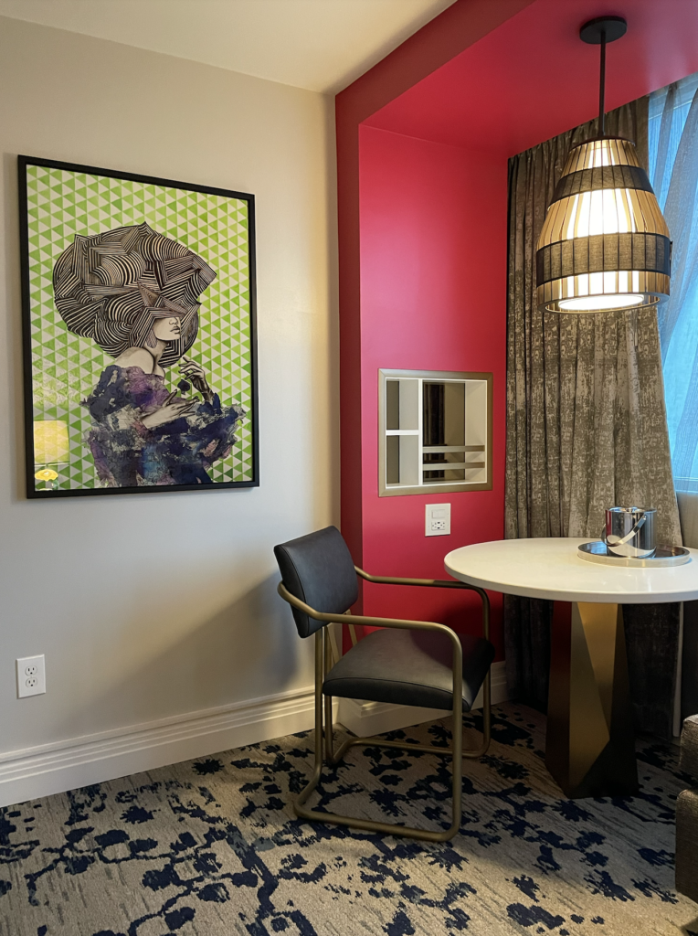 Seating vignette in a guest room at the Colee hotel with a pop of fuschia on the walls
