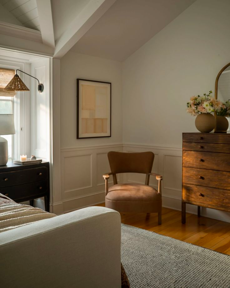 Transitional bedroom with wainscoting and wooden details. A wood and leather armchair in the corner