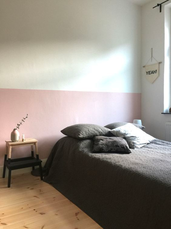 A minimalist bedroom with a pale pink painted on the bottom half of the wall