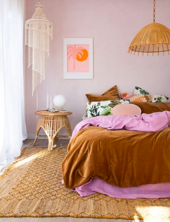 Fun and colorful boho bedroom with pink and rust-colored bedding, a jute rug and two eclectic boho light fixtures