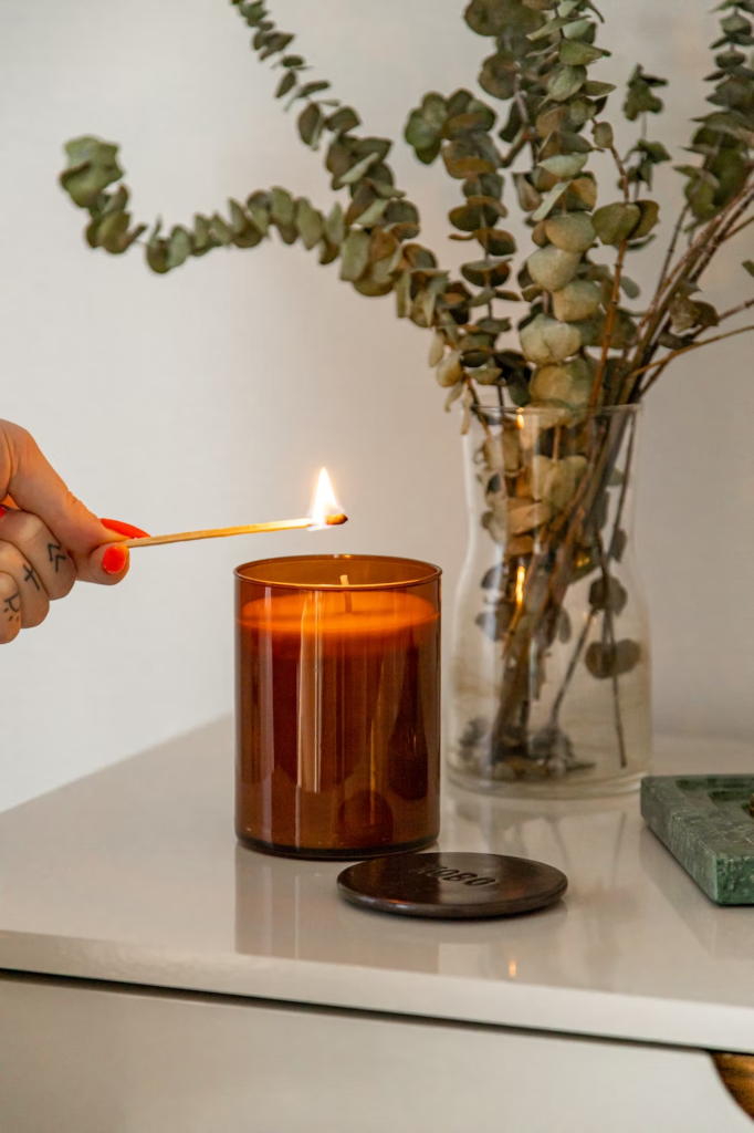 Lighting a candle next to a vase of dried eucalyptus