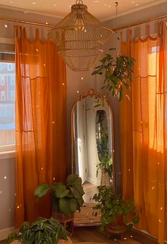 sunny room with a gold vintage and ornate mirror. Semi-sheer orange curtains